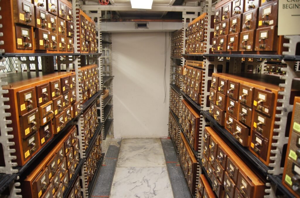 Wooden card catalogue drawers with brass label holders, viewed at an angle down the aisle.