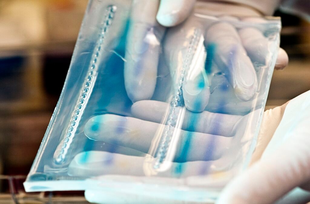 A technician lifting a cast agarose slab from its tray, held flat in gloved hands.