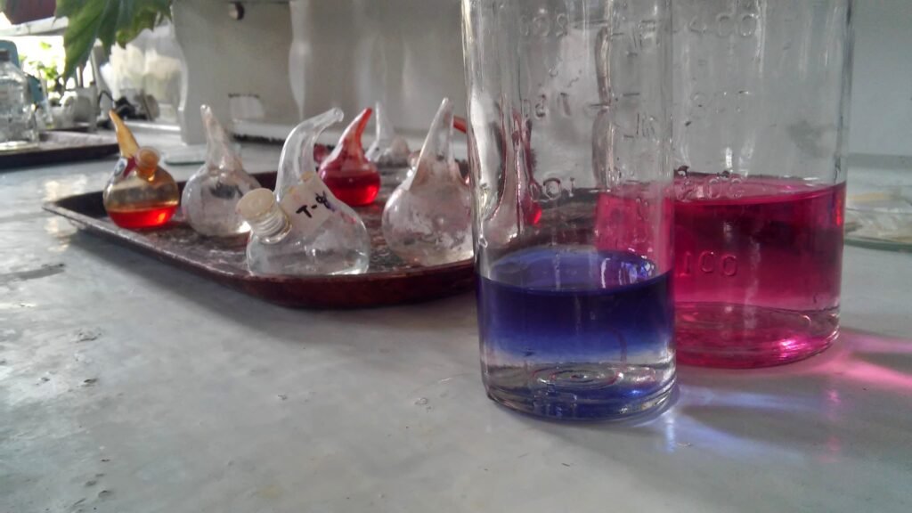 Laboratory flasks and volumetric glassware arranged in a row on a bench under even light.