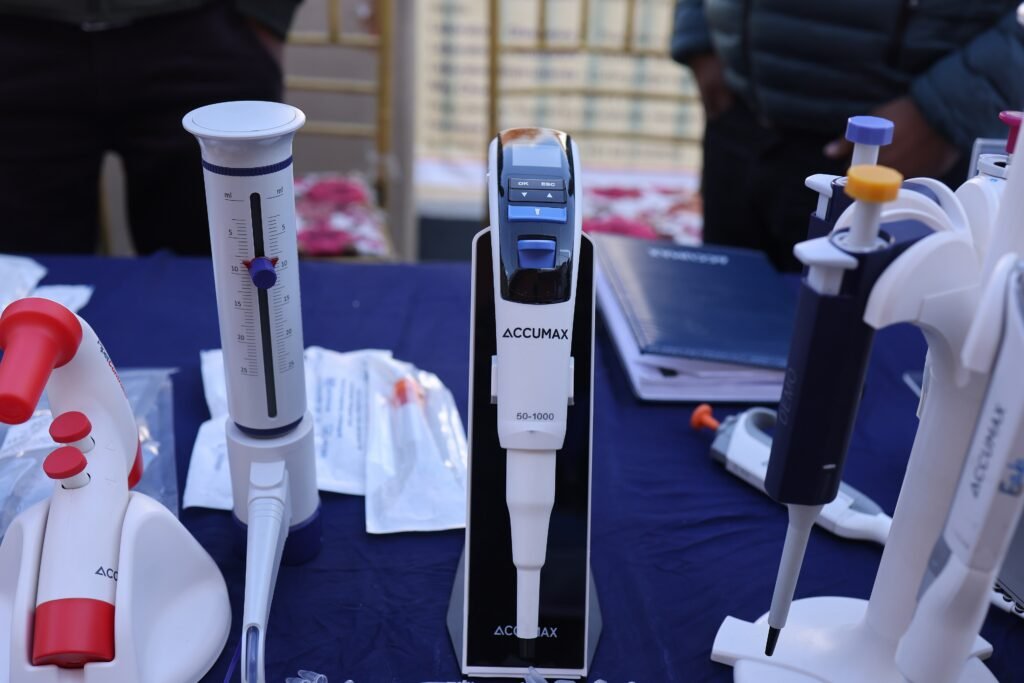 A handheld electronic micropipette resting beside labelled tubes on a laboratory bench.