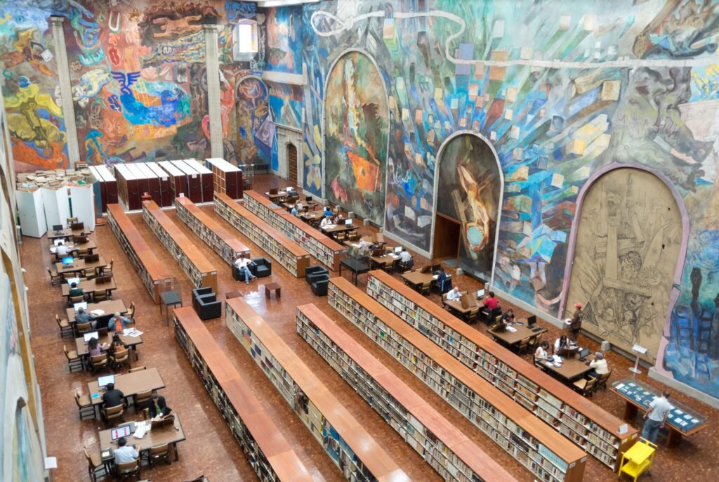 A high-ceilinged library reading room with long tables and lamps receding into the distance.