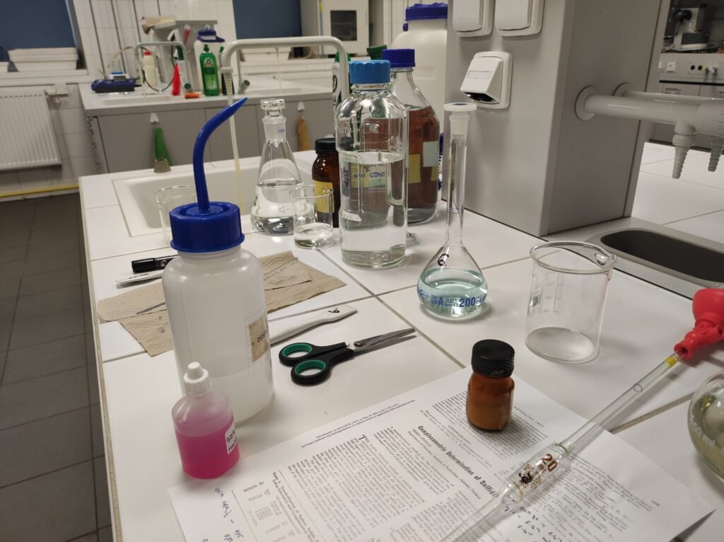 A long laboratory bench seen end-on, glassware and racks arranged along its length under even overhead light.